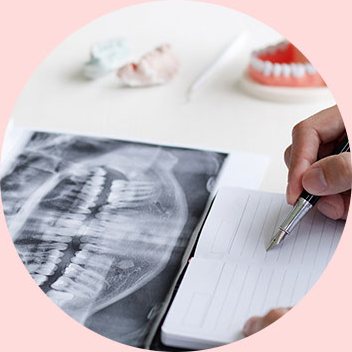 파노라마 X-ray를 보며 진단 내용을 기록하는 손